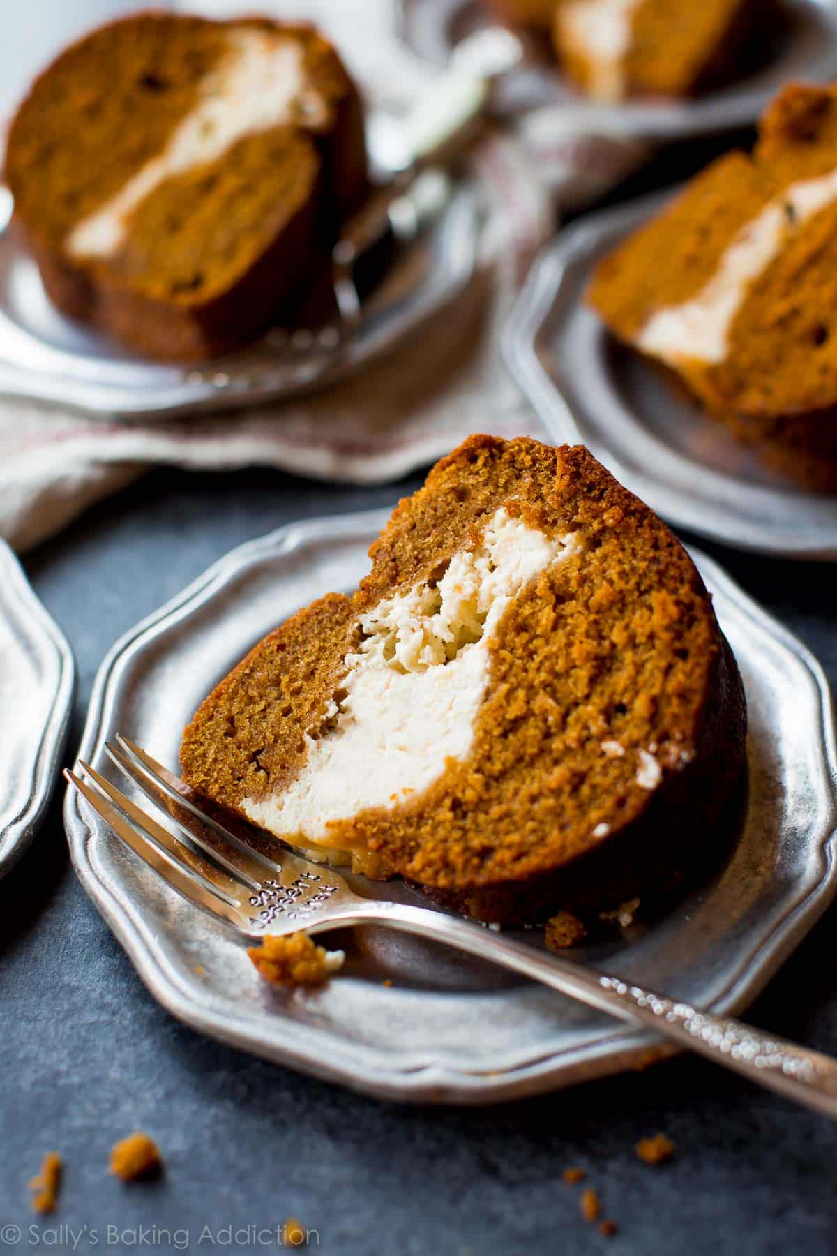 slices of pumpkin cream cheese bundt cake on silver plates with forks