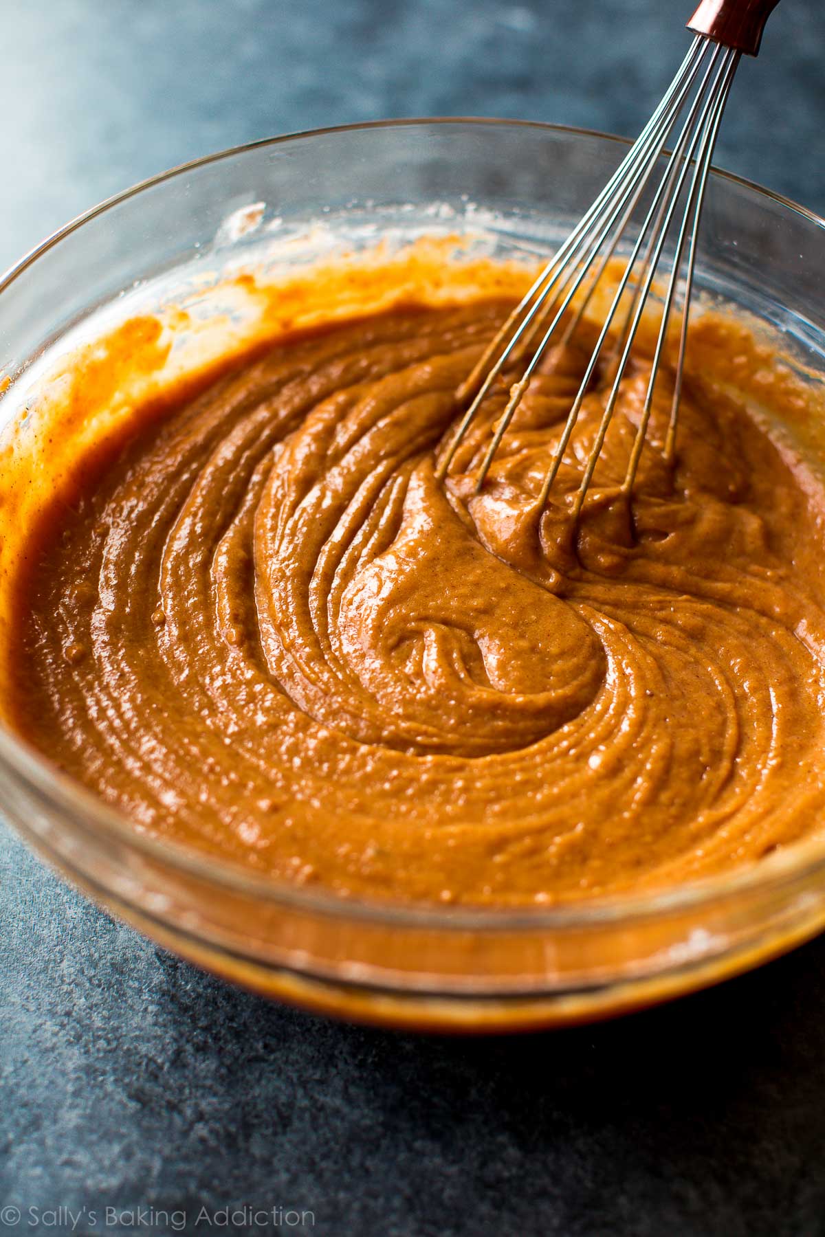 pumpkin cake batter in a glass bowl with a whisk
