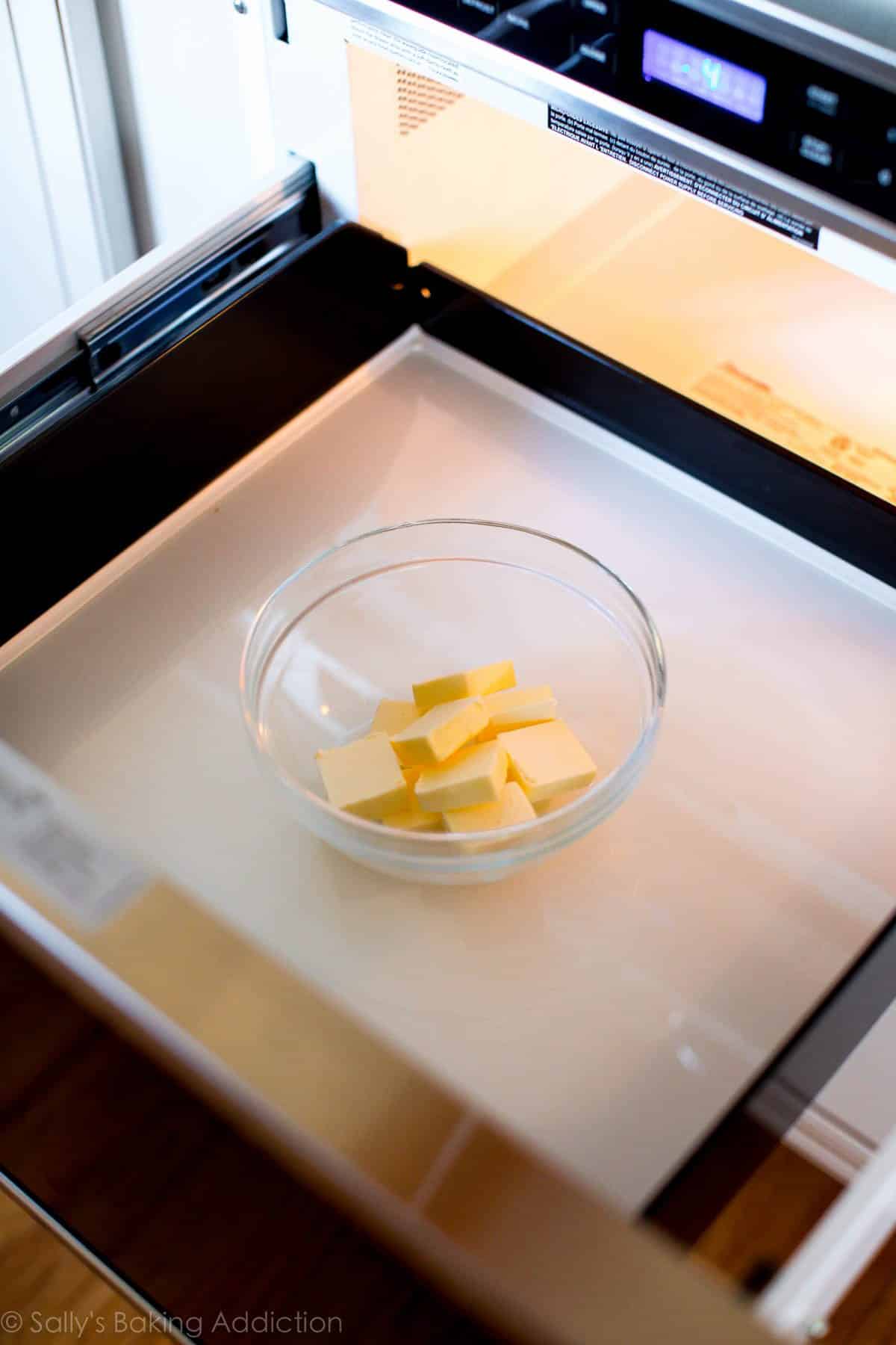 glass bowl with butter inside on an opened drawer microwave