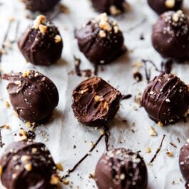 chocolate hazelnut crunch truffles on parchment paper with a bite taken from one showing the inside