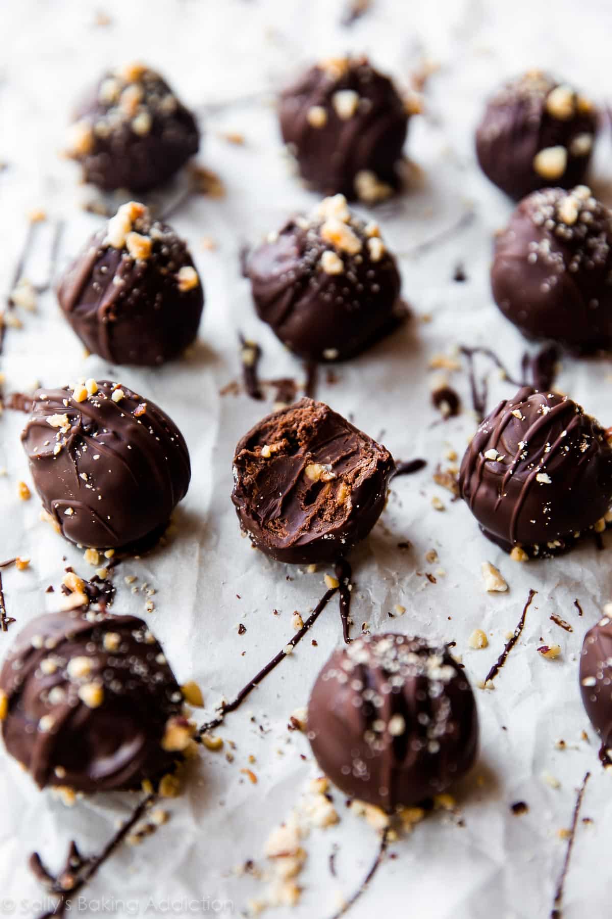 chocolate hazelnut crunch truffles on parchment paper with a bite taken from one showing the inside