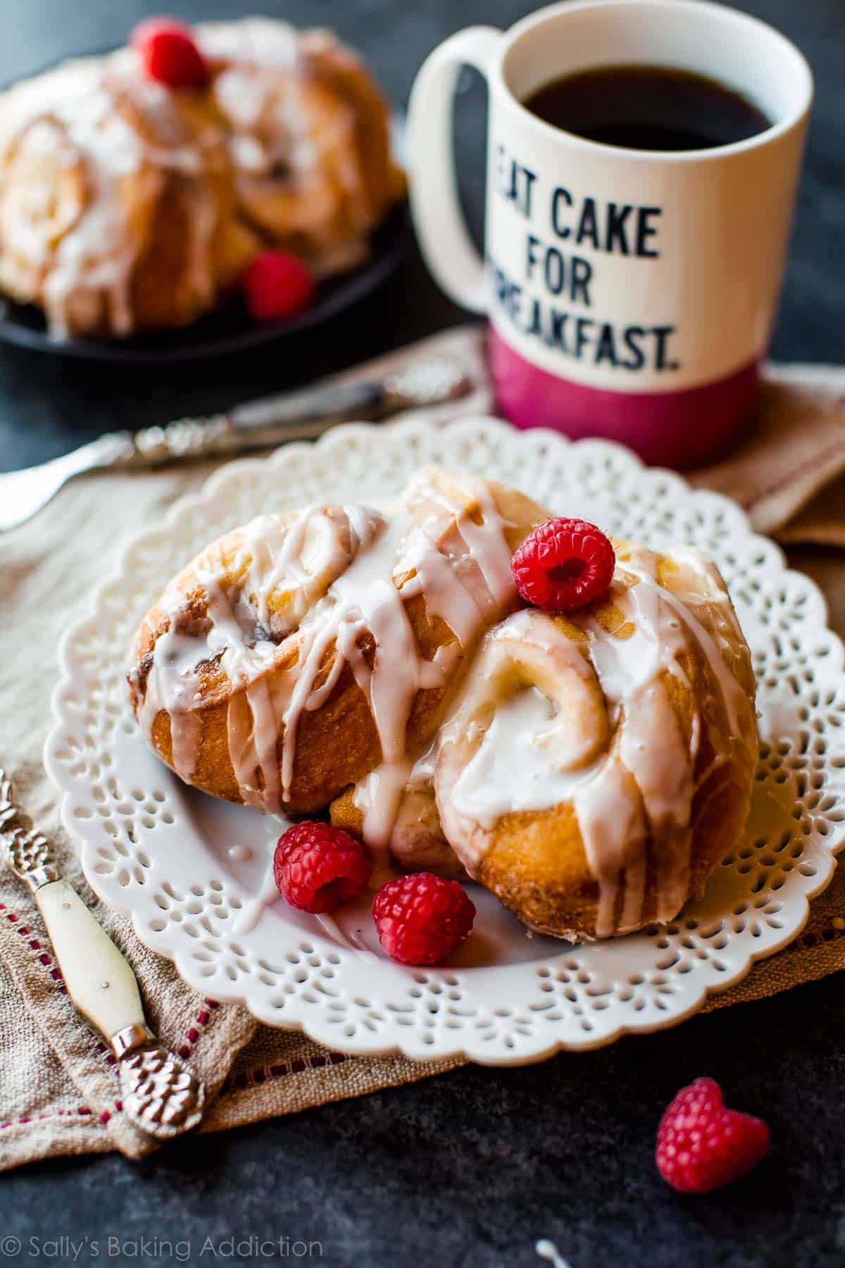 serving of cinnamon roll wreath on a white plate with a cup of coffee