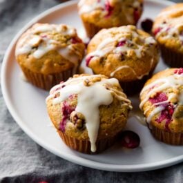 cranberry cardamom spice muffins with orange icing on a white plate