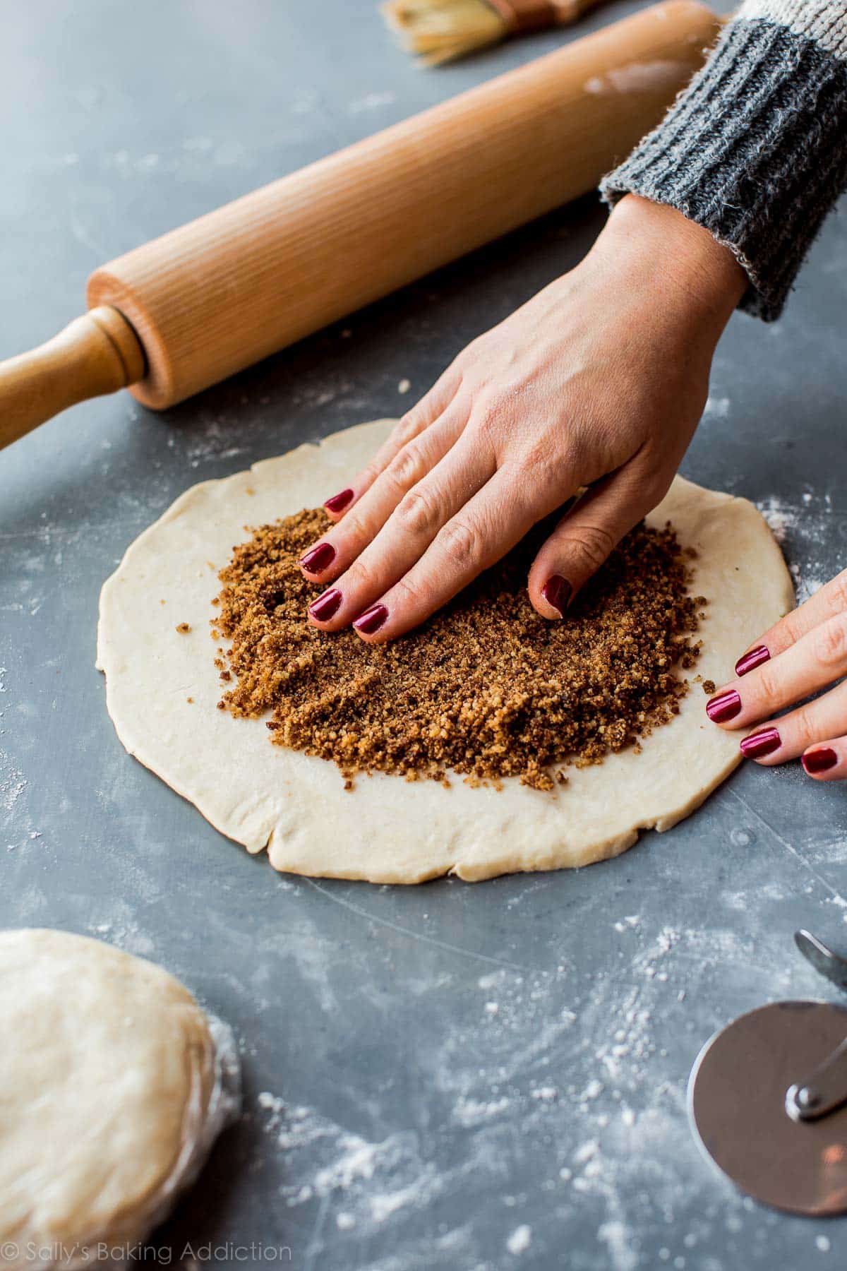 hands spreading rugelach filling onto circle of cookie dough