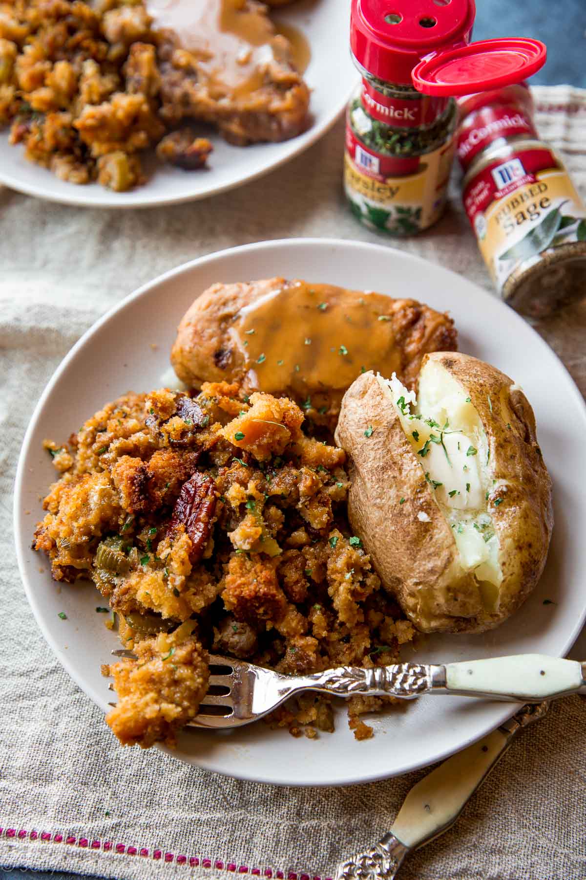 cornbread stuffing on a white plate with a baked potato and turkey