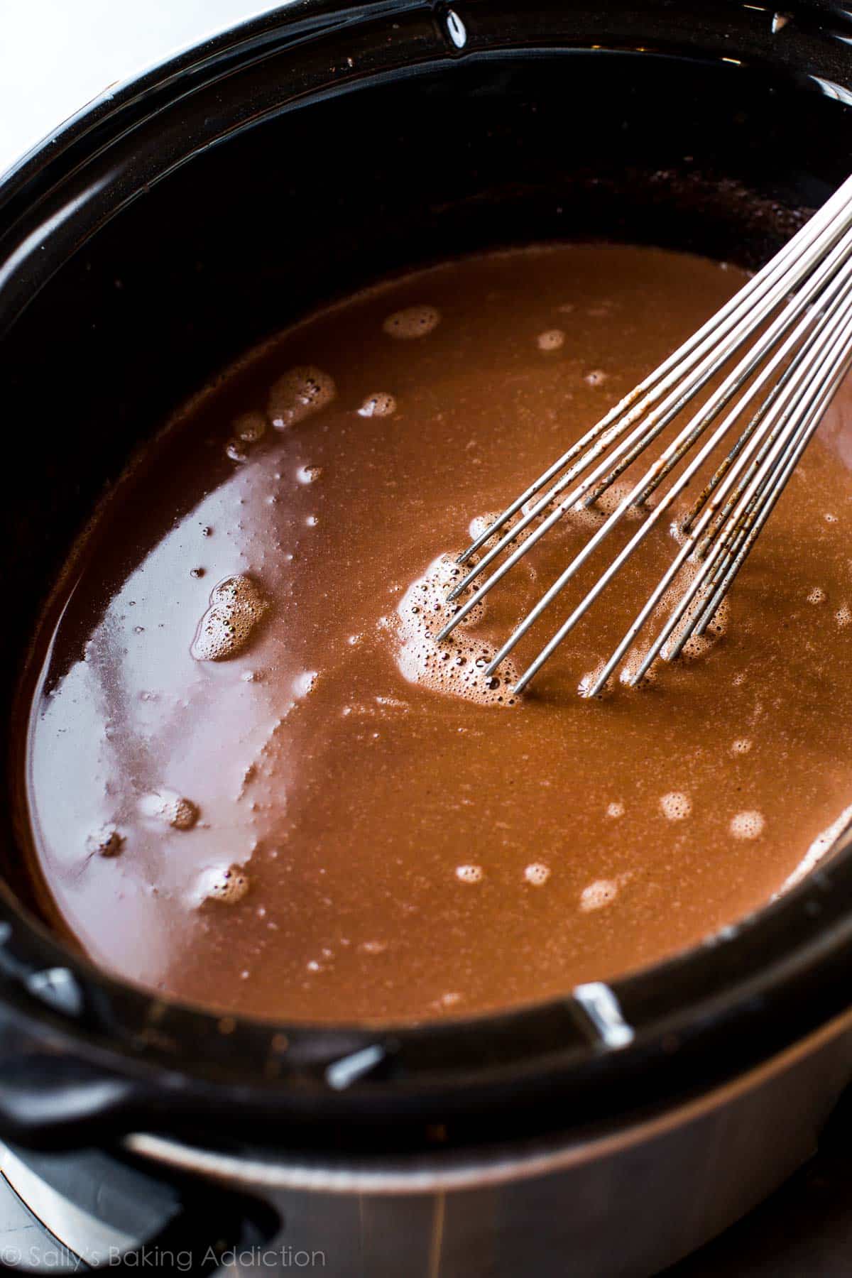 hot chocolate in a slow cooker with a metal whisk