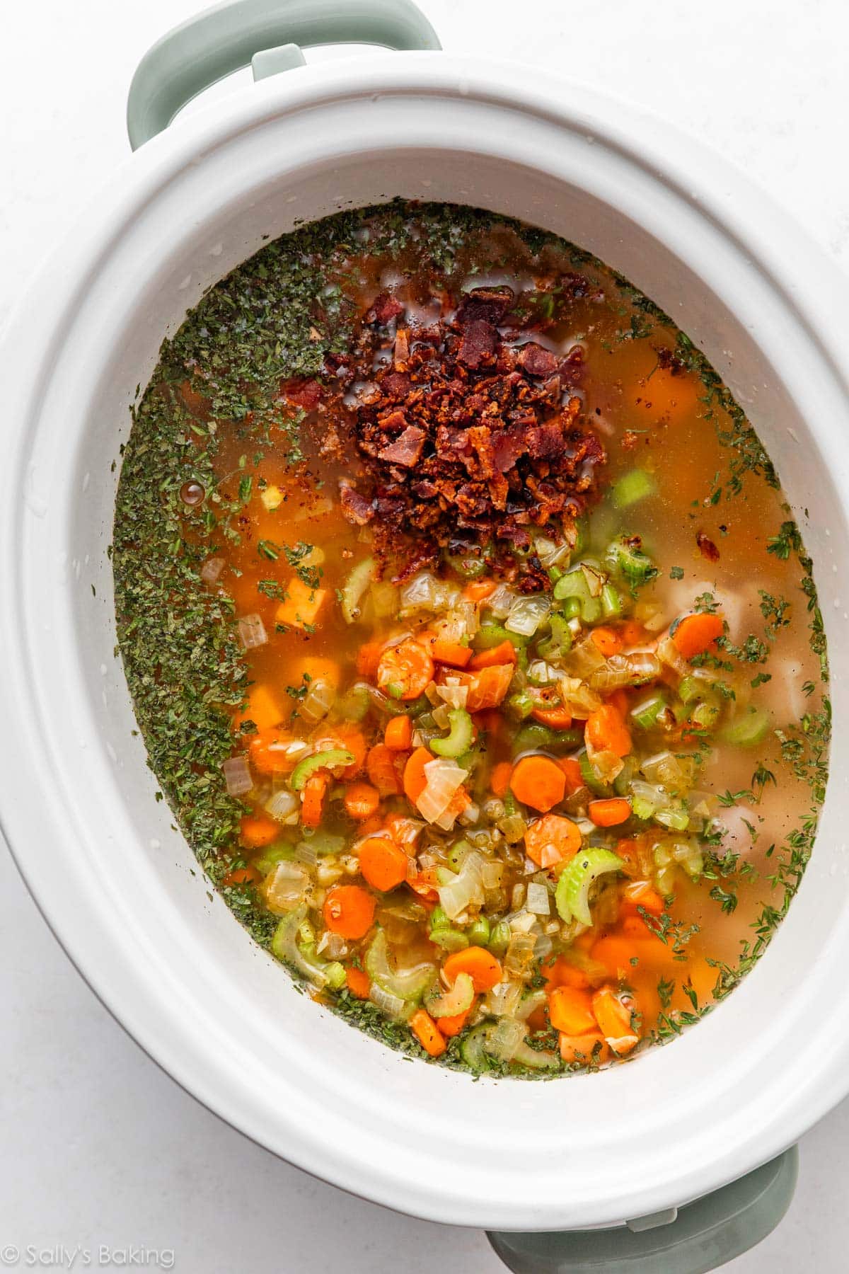 broth, herbs, and vegetables in slow cooker.