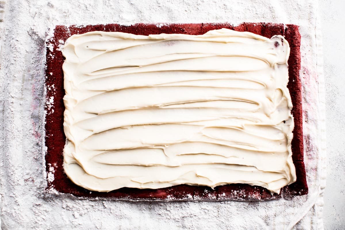 cream cheese frosting spread onto red velvet sponge cake