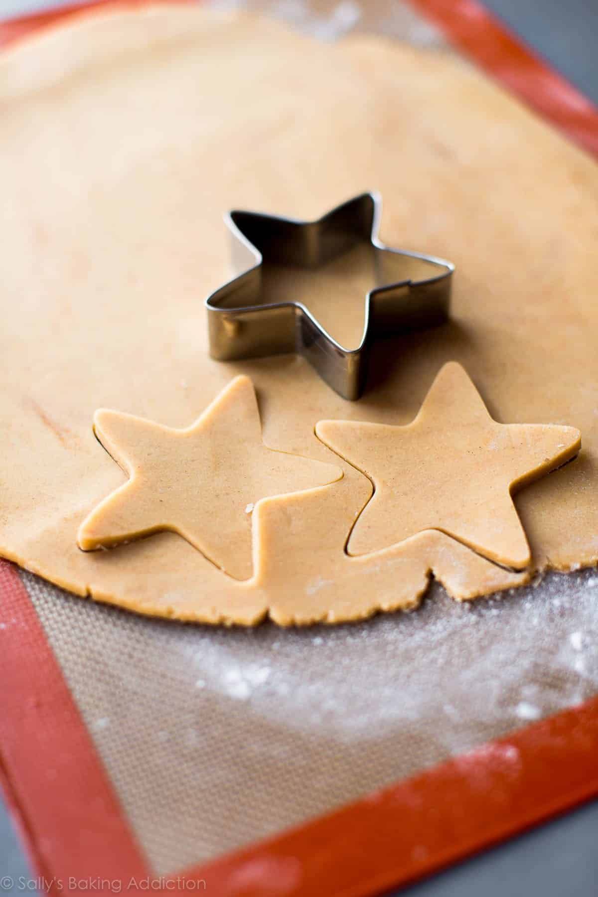 maple sugar cookie dough rolled out on a silpat baking mat with a star cookie cutter