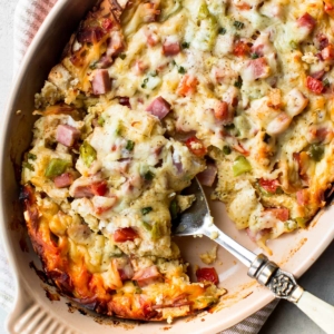 overhead image of ham and cheese strata in a casserole dish with a serving spoon