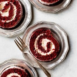 slices of red velvet cake roll on silver plates with a fork