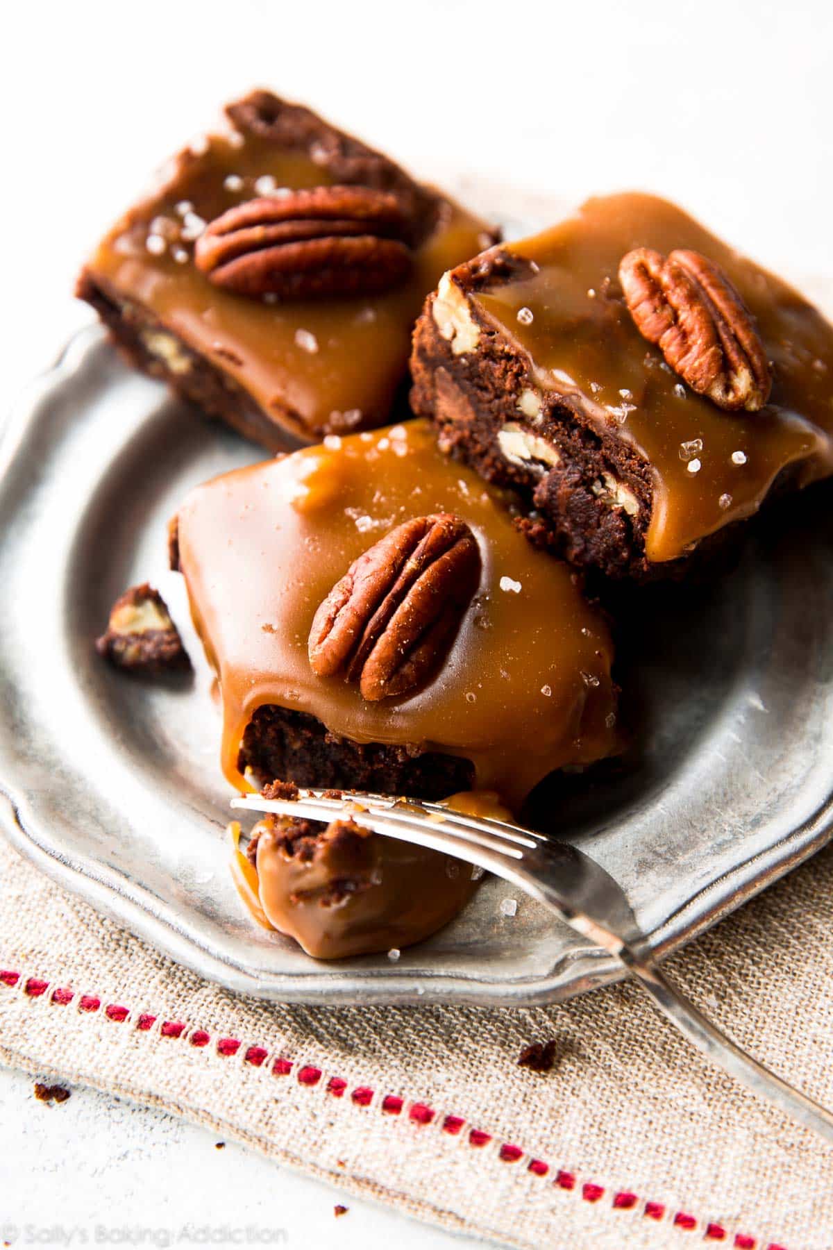 salted caramel turtle brownies on a silver plate with a fork