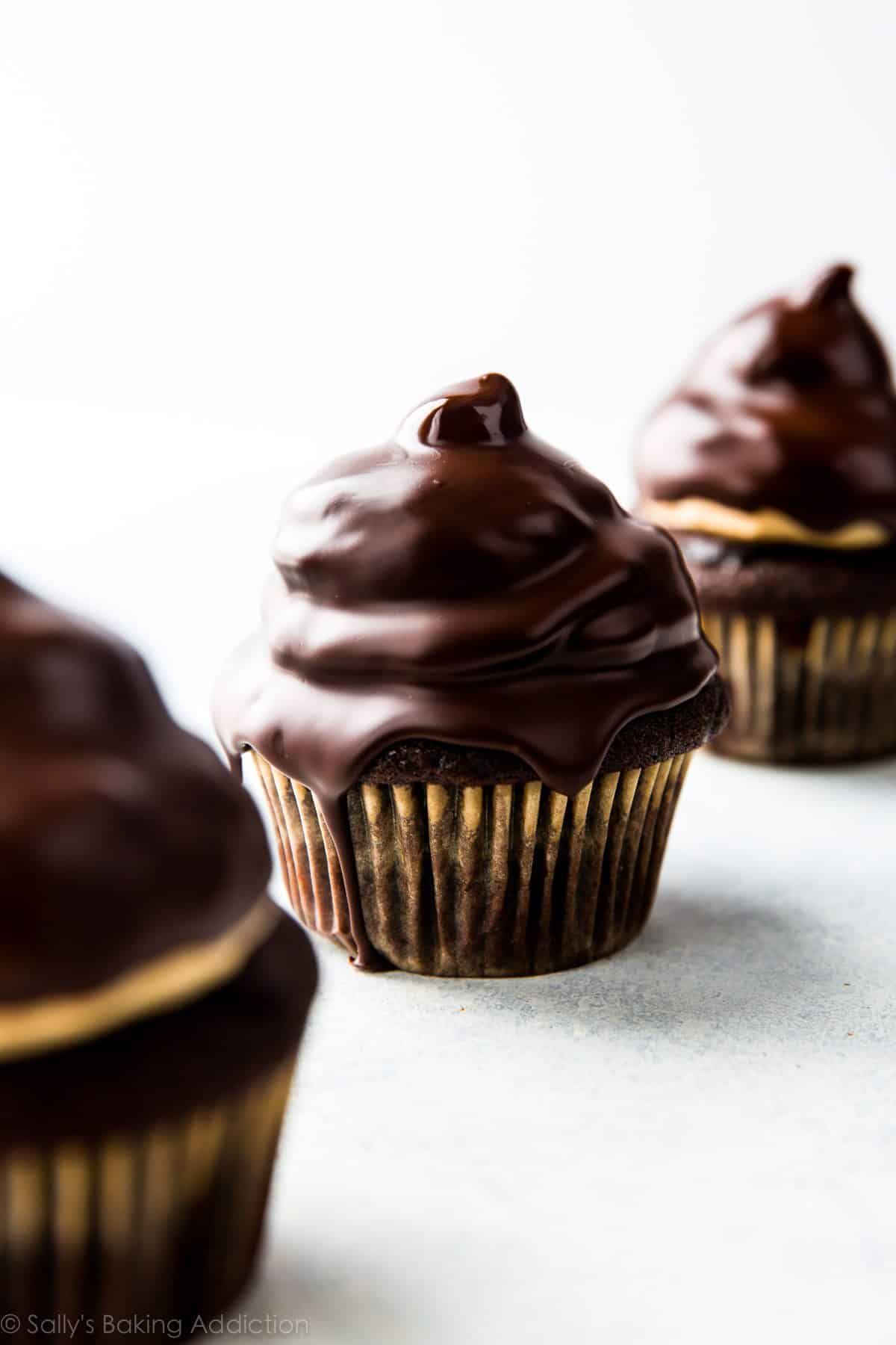 chocolate cupcakes with peanut butter meringue frosting underneath a chocolate shell coating