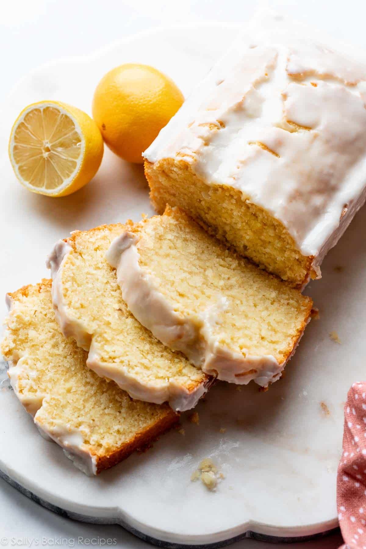 lemon pound cake loaf with 3 slices cut on marble serving tray.