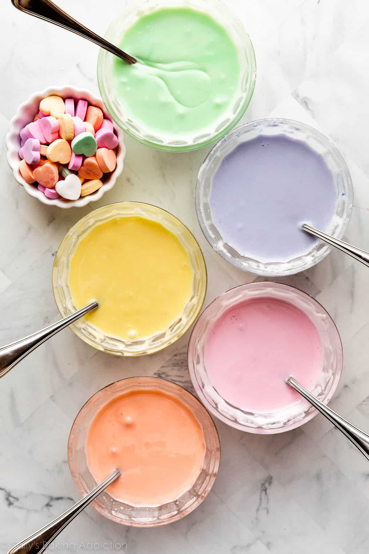 5 small glass bowls of pastel colored icing.