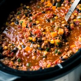 taco spice chili in a slow cooker with a ladle