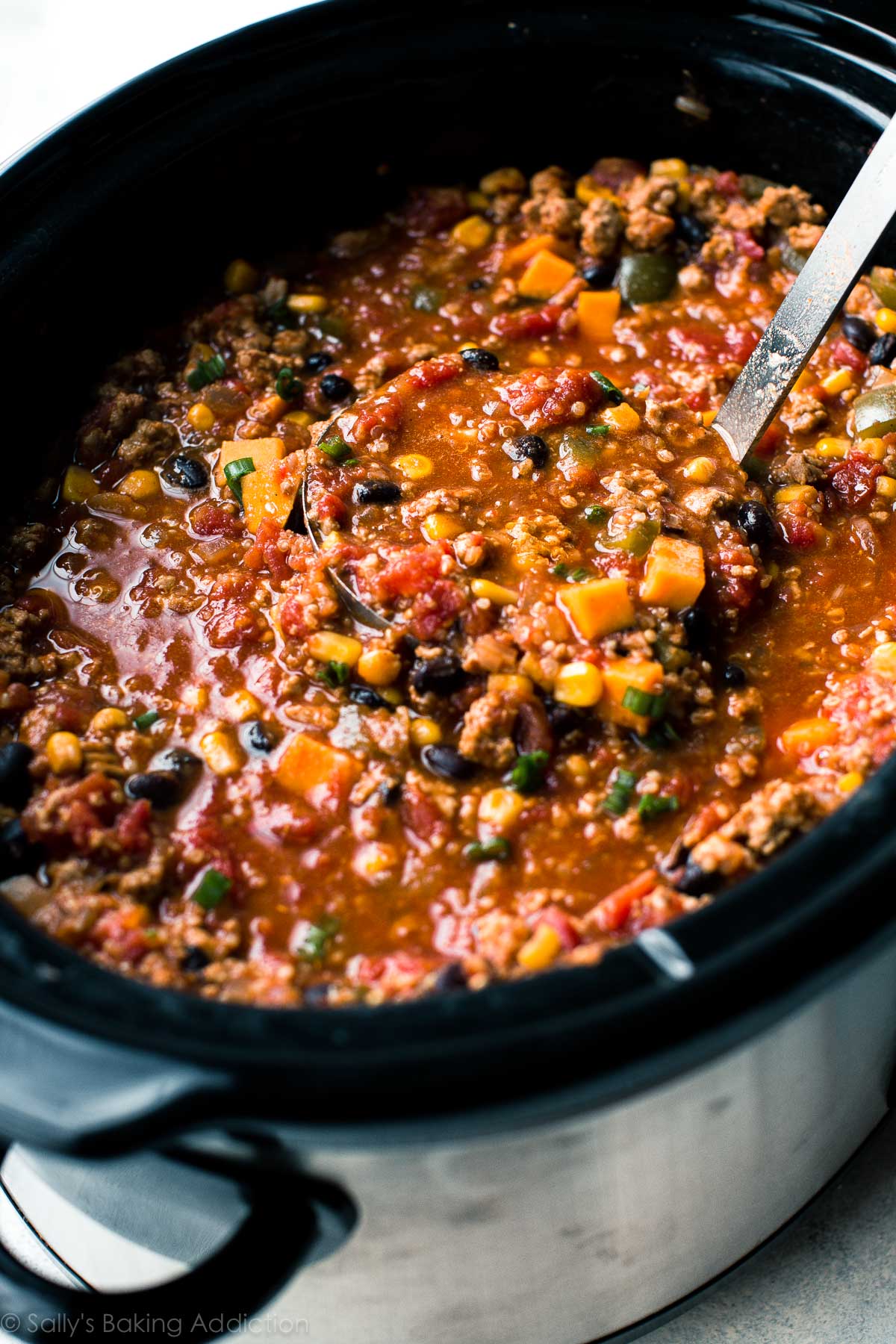 taco spice chili in a slow cooker with a ladle