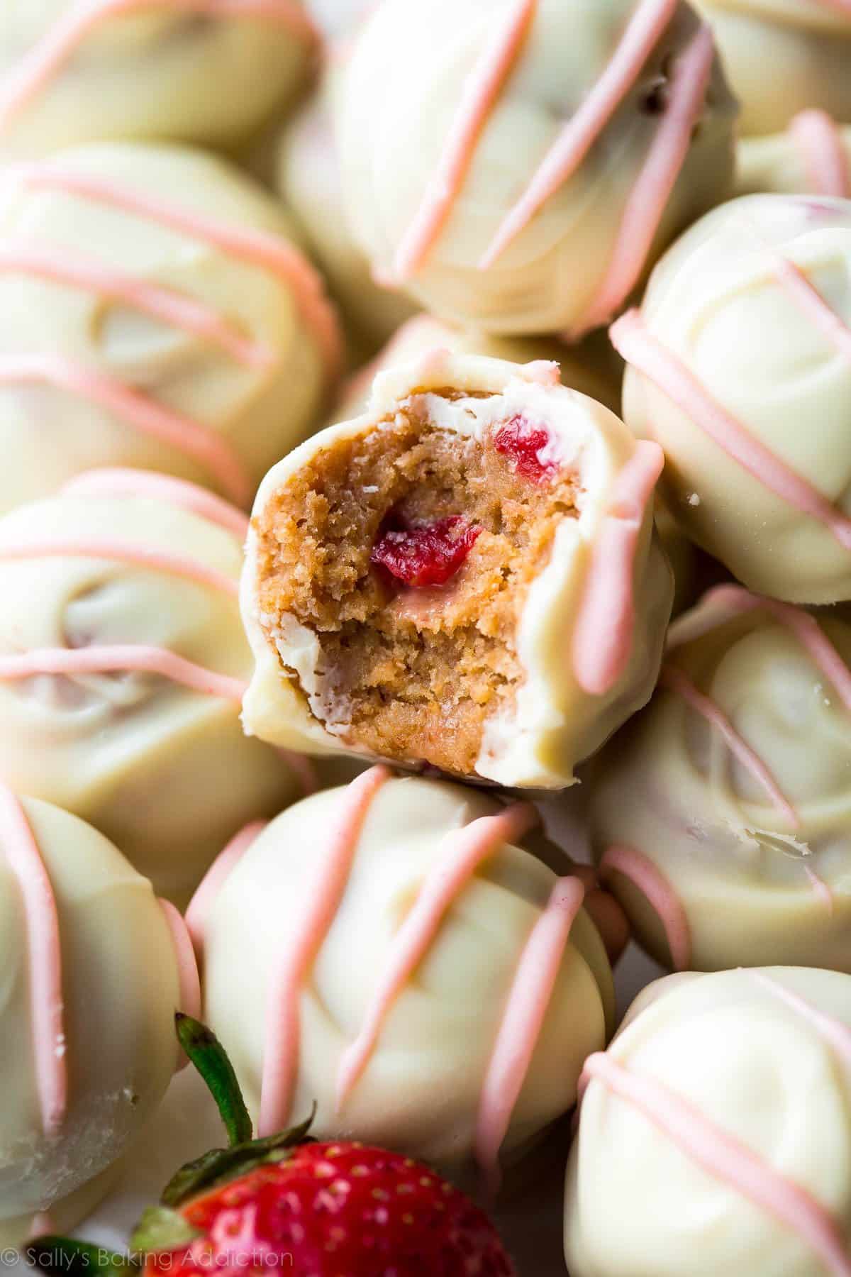 zoomed in image of strawberry cheesecake truffles with a bite out of one showing the inside