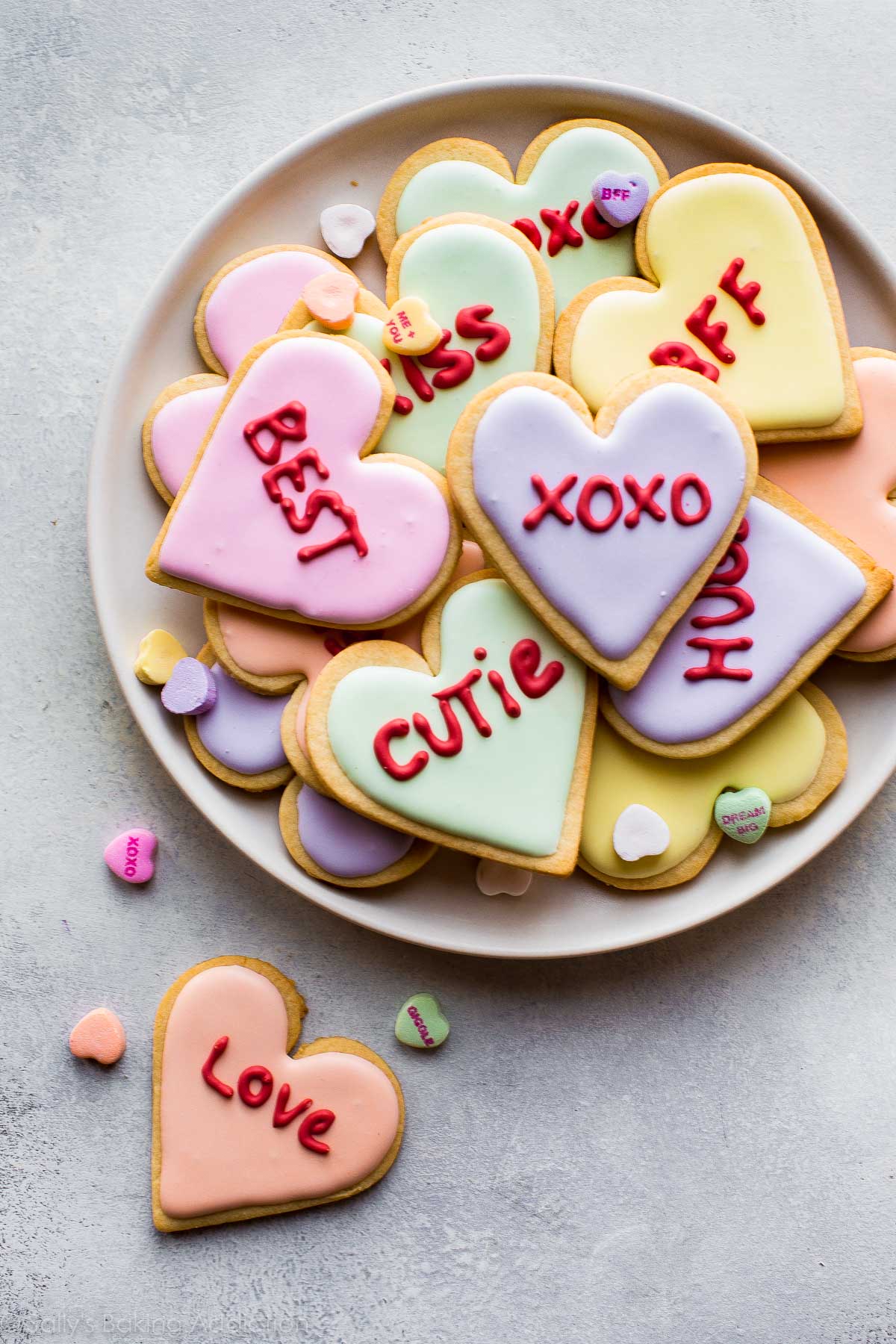 conversation heart sugar cookies decorated with colorful royal icing on a white plate