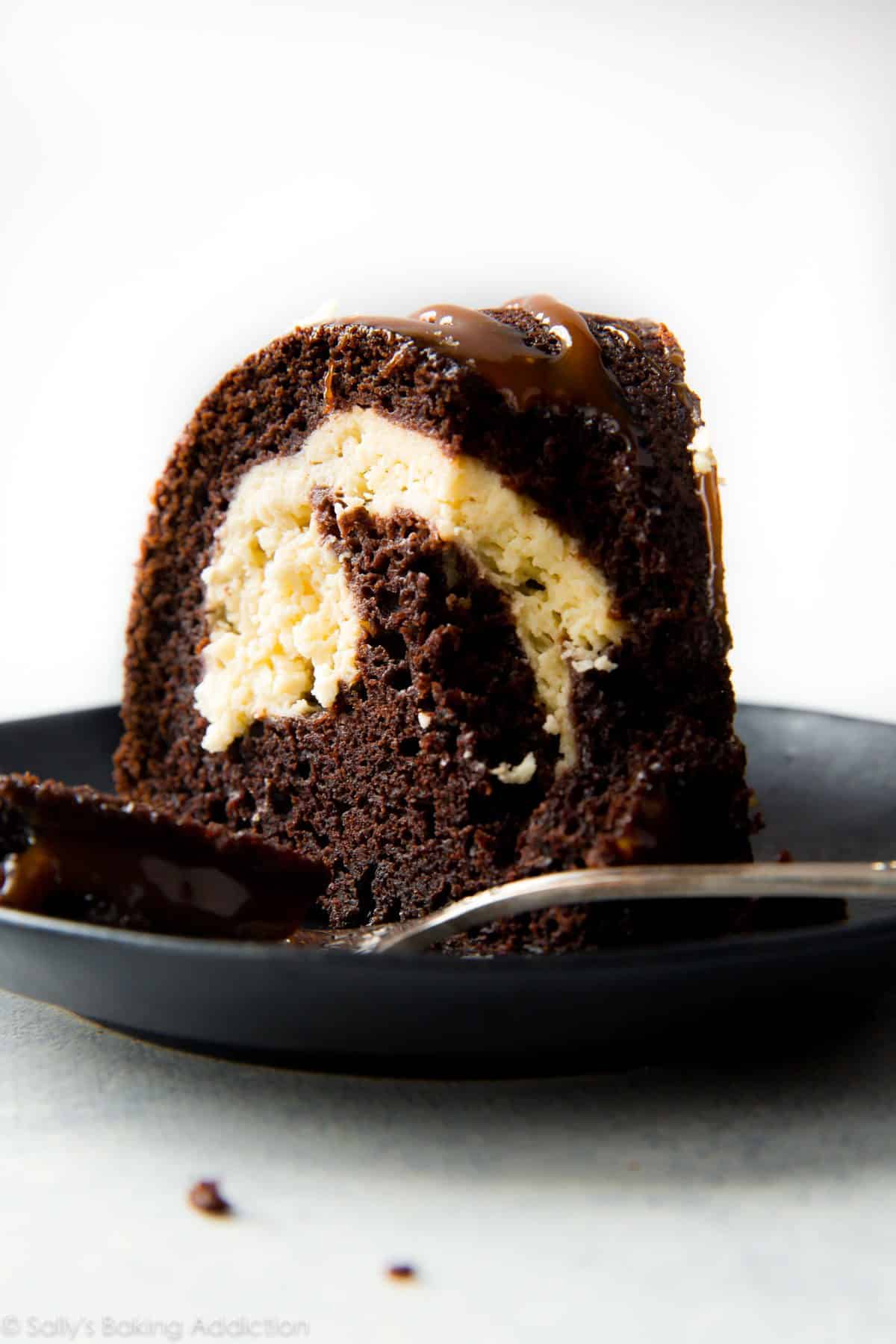 slice of chocolate cream cheese bundt cake on a black plate with a fork