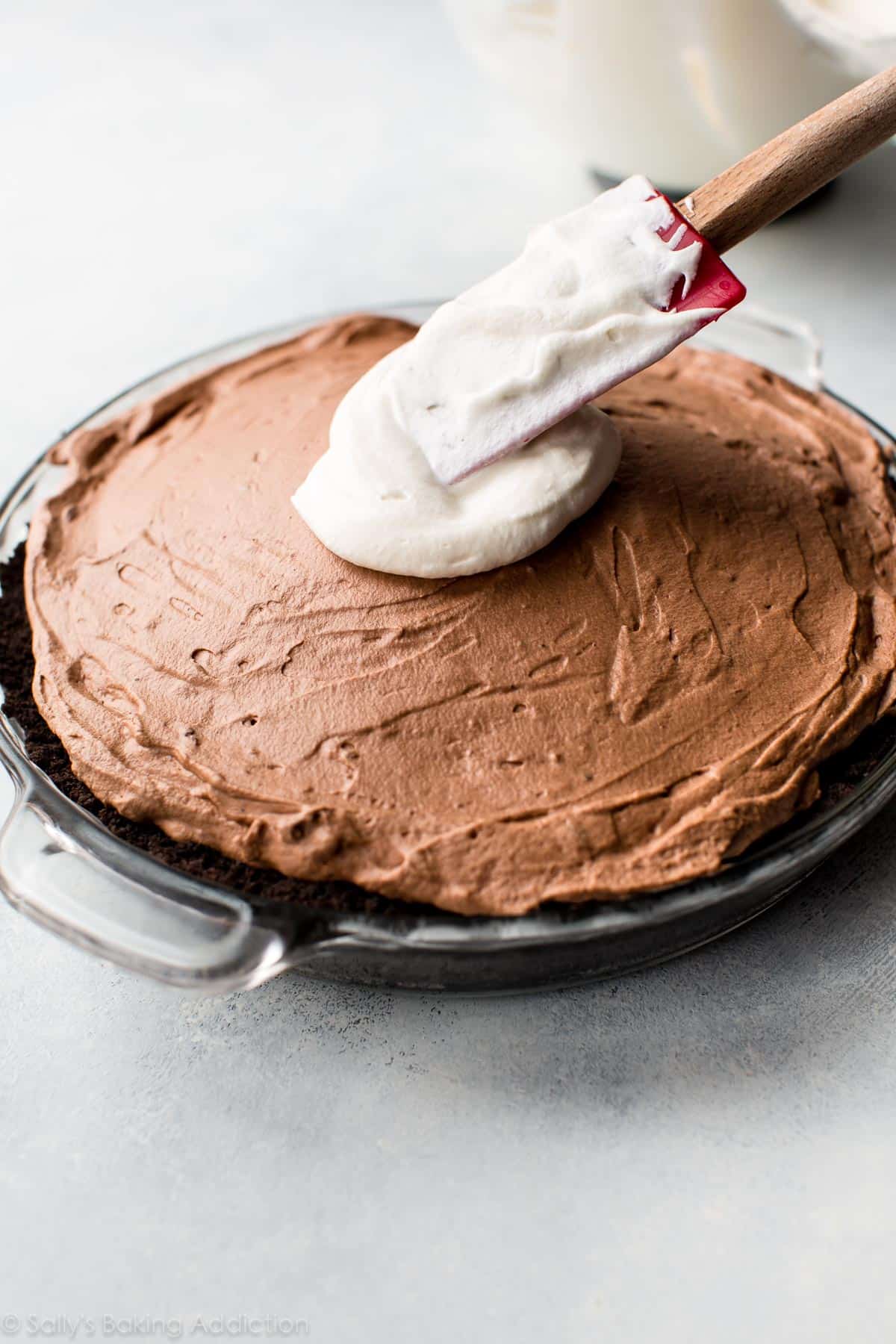 spreading whipped cream onto chocolate mousse pie