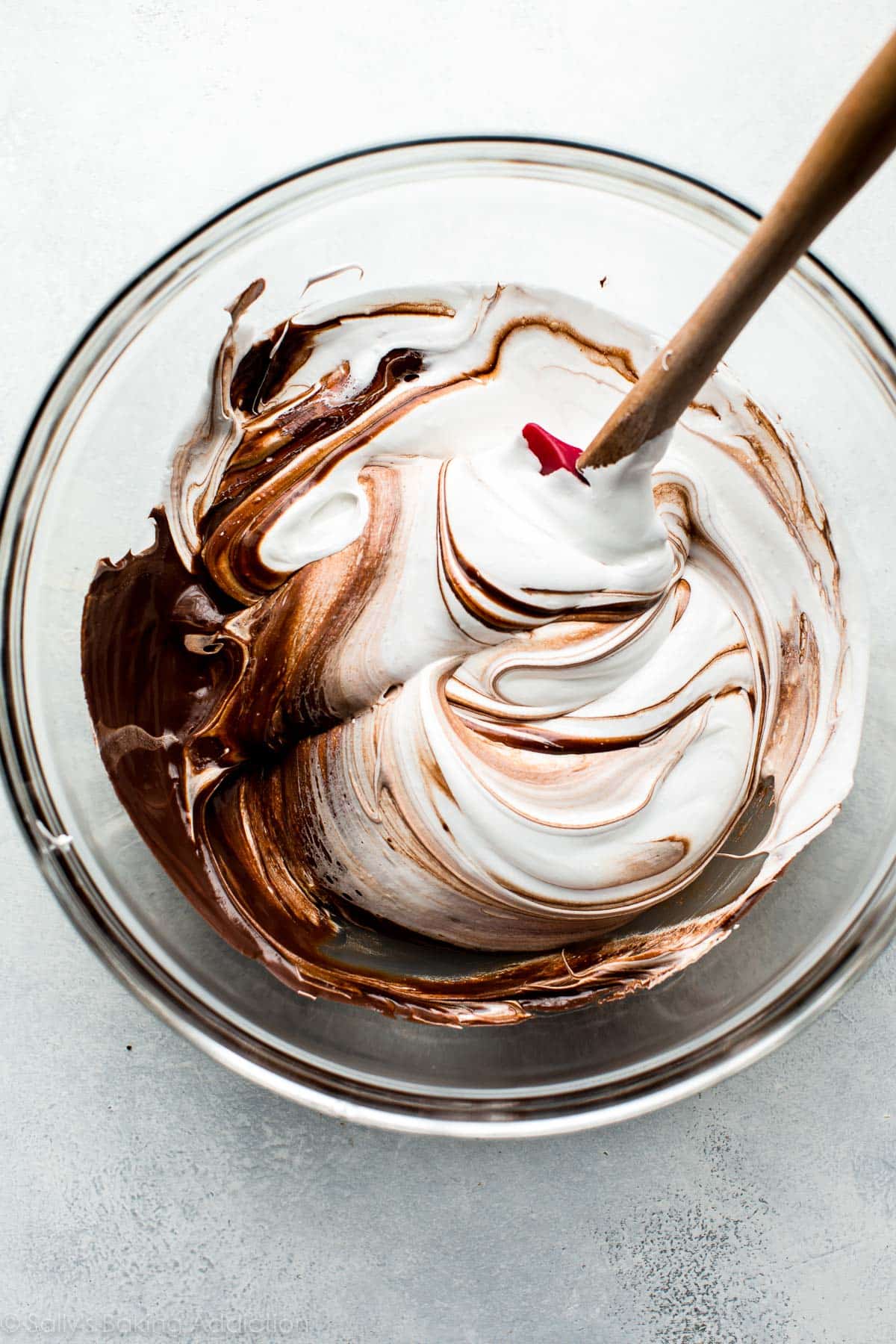 folding the meringue into the melted chocolate in a glass bowl