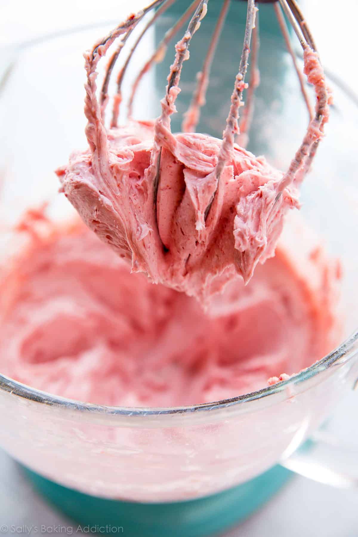 strawberry frosting in a glass stand mixer bowl with a whisk attachment