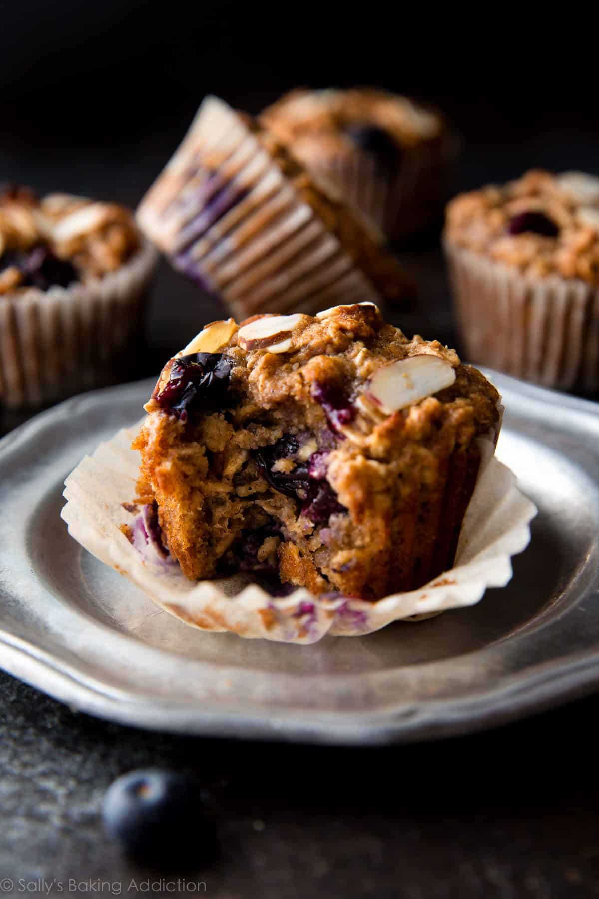 blueberry almond muffin on a silver plate with a bite taken from it