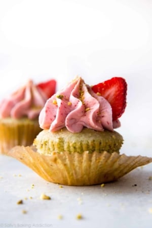pistachio cupcake topped with strawberry frosting and a slice of strawberry