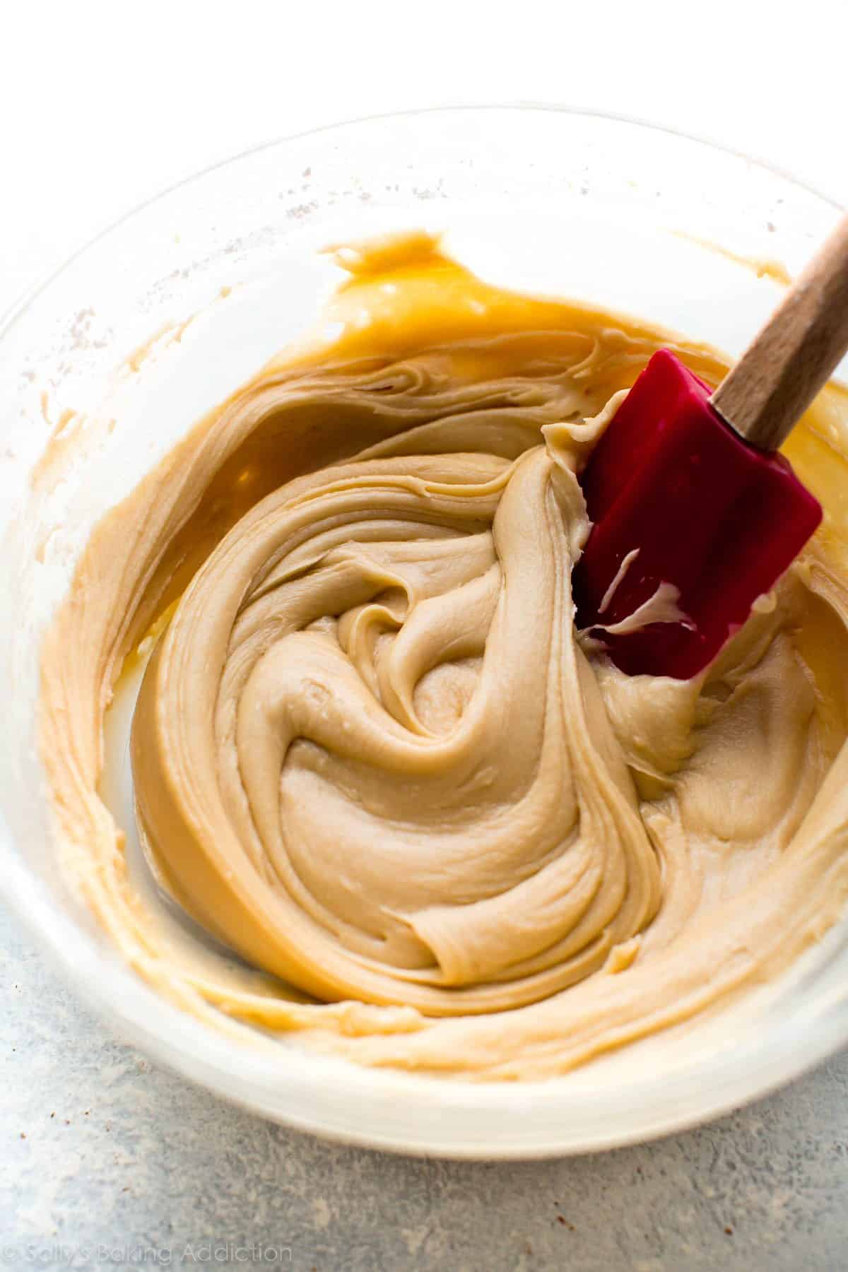 salted caramel frosting in a glass bowl with a red spatula