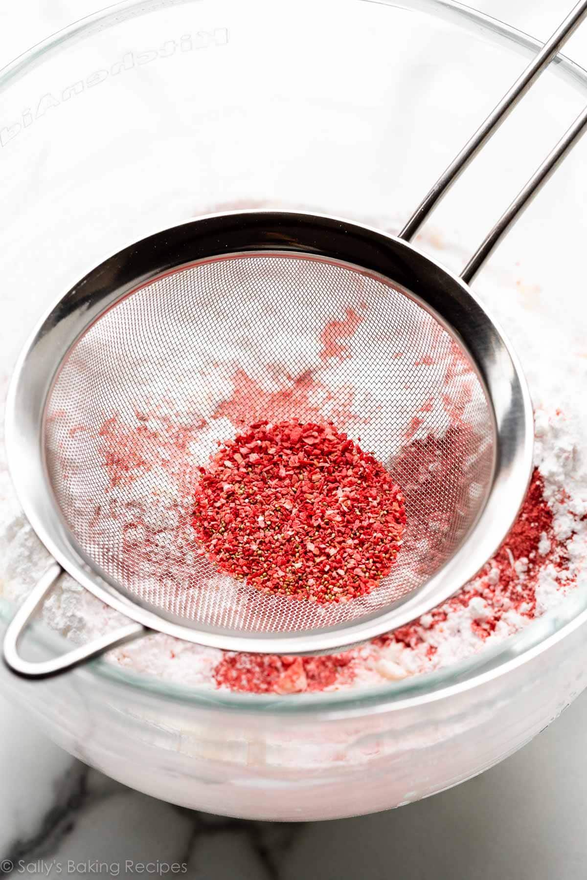 sieve with red pieces of freeze-dried strawberries in it.