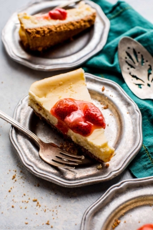 slices of cheesecake with strawberry topping on a silver plates with a fork