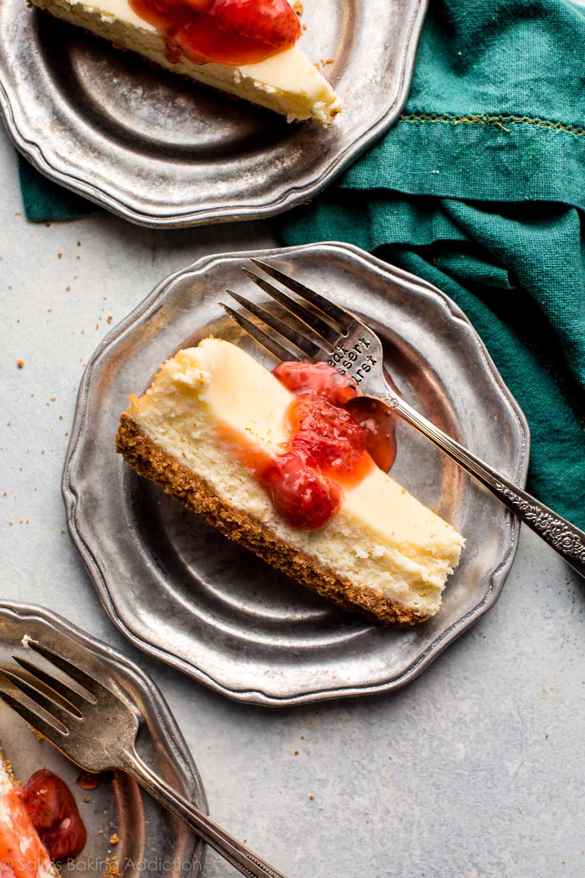 slices of cheesecake with strawberry topping on a silver plates with a fork