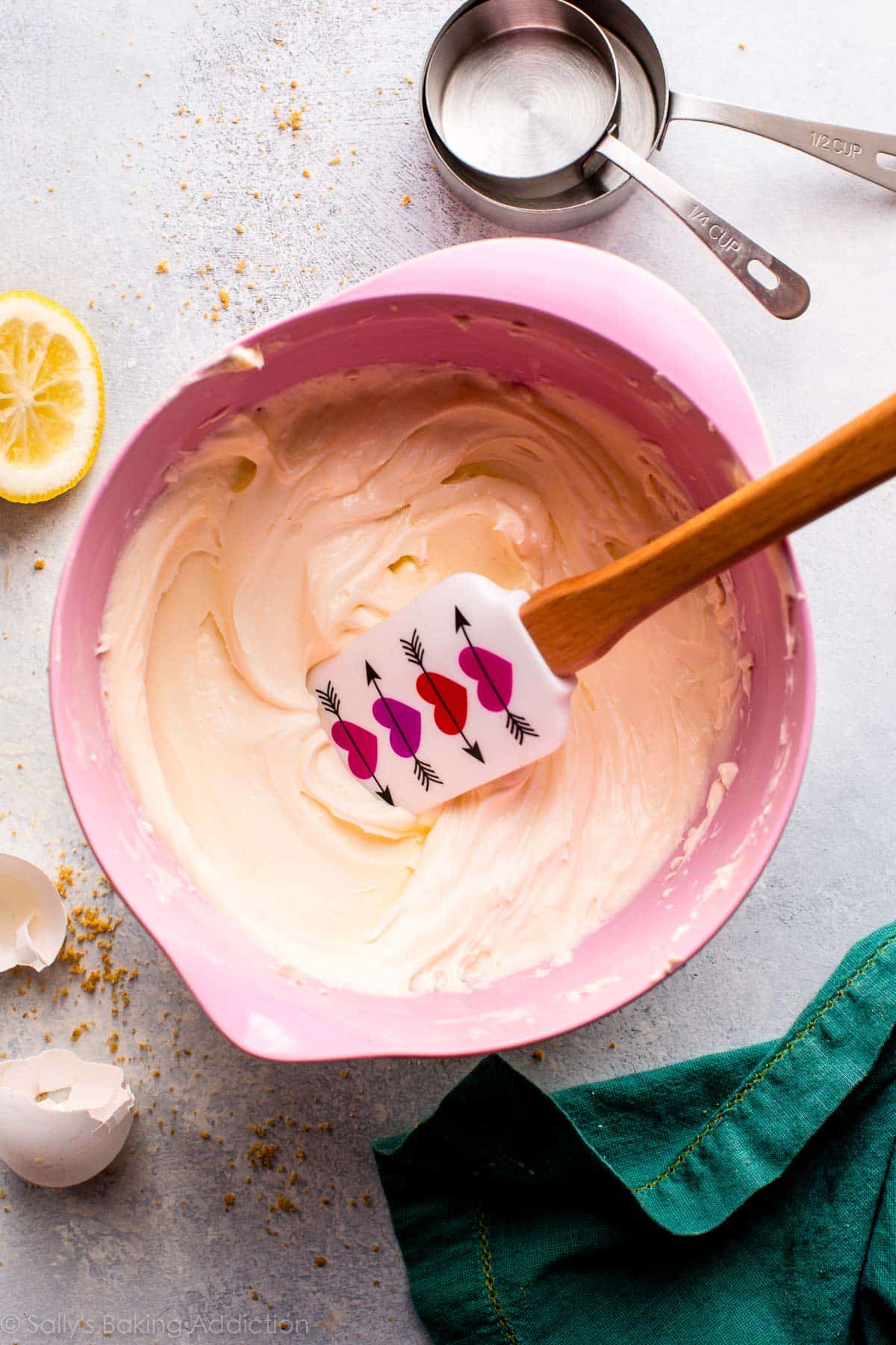 overhead image of cheesecake batter in a pink bowl with a spatula