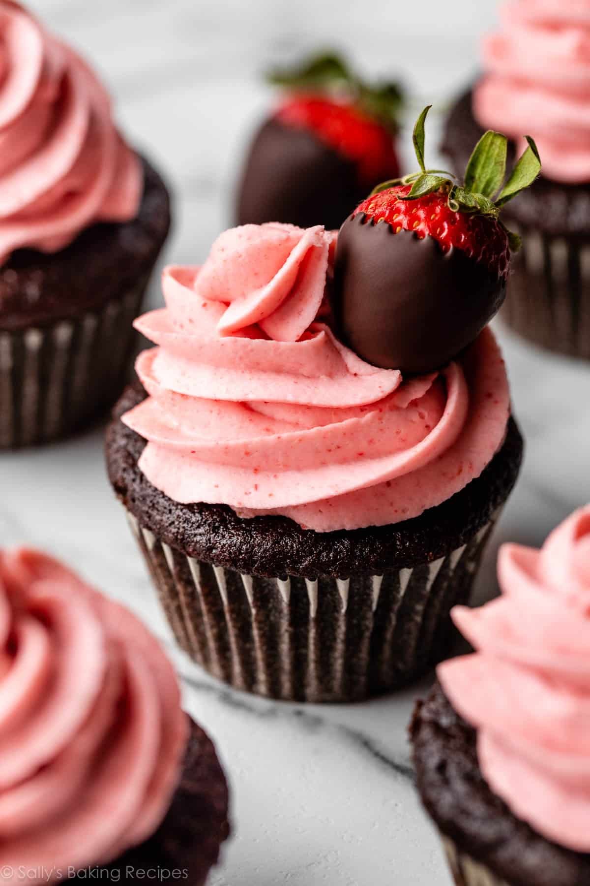 chocolate cupcake with strawberry frosting on top and garnished with chocolate covered strawberry.