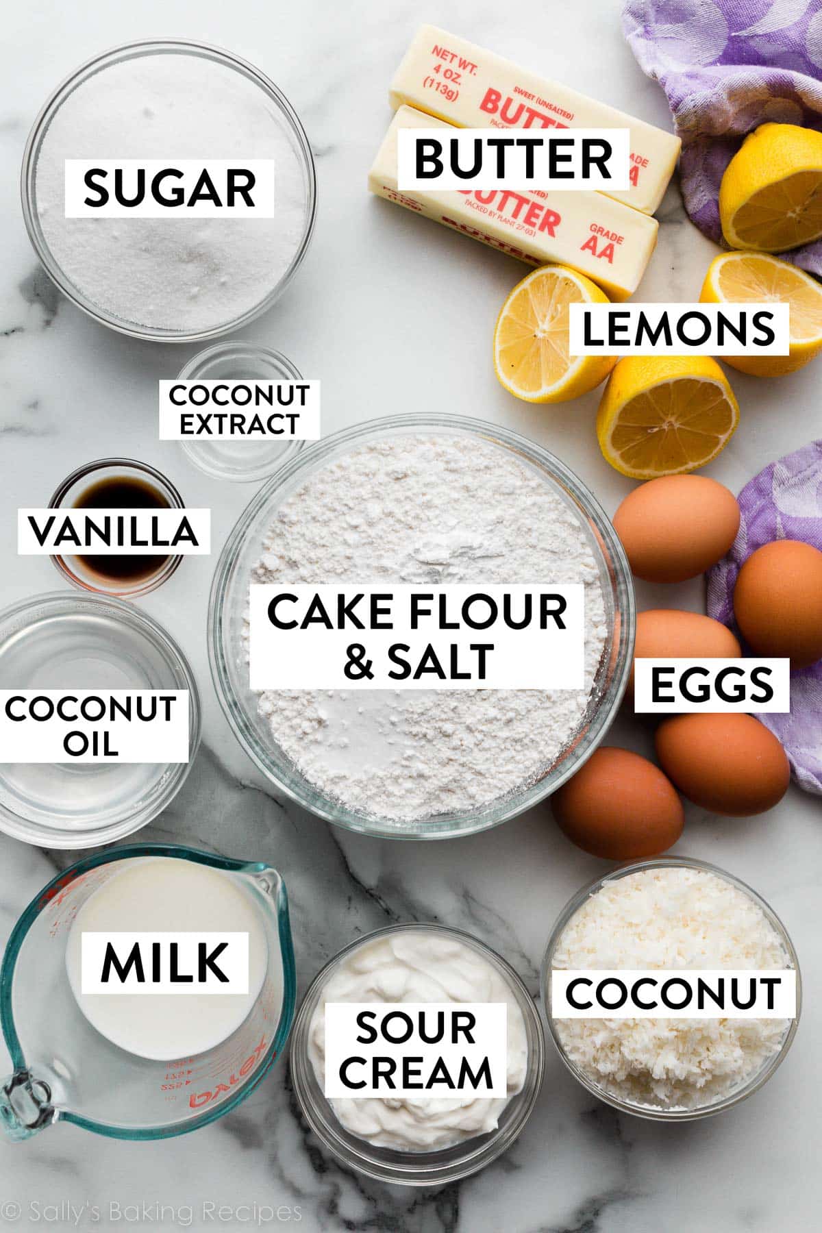 ingredients on counter including eggs, butter, cut lemons, cake flour, coconut, sour cream, and more.