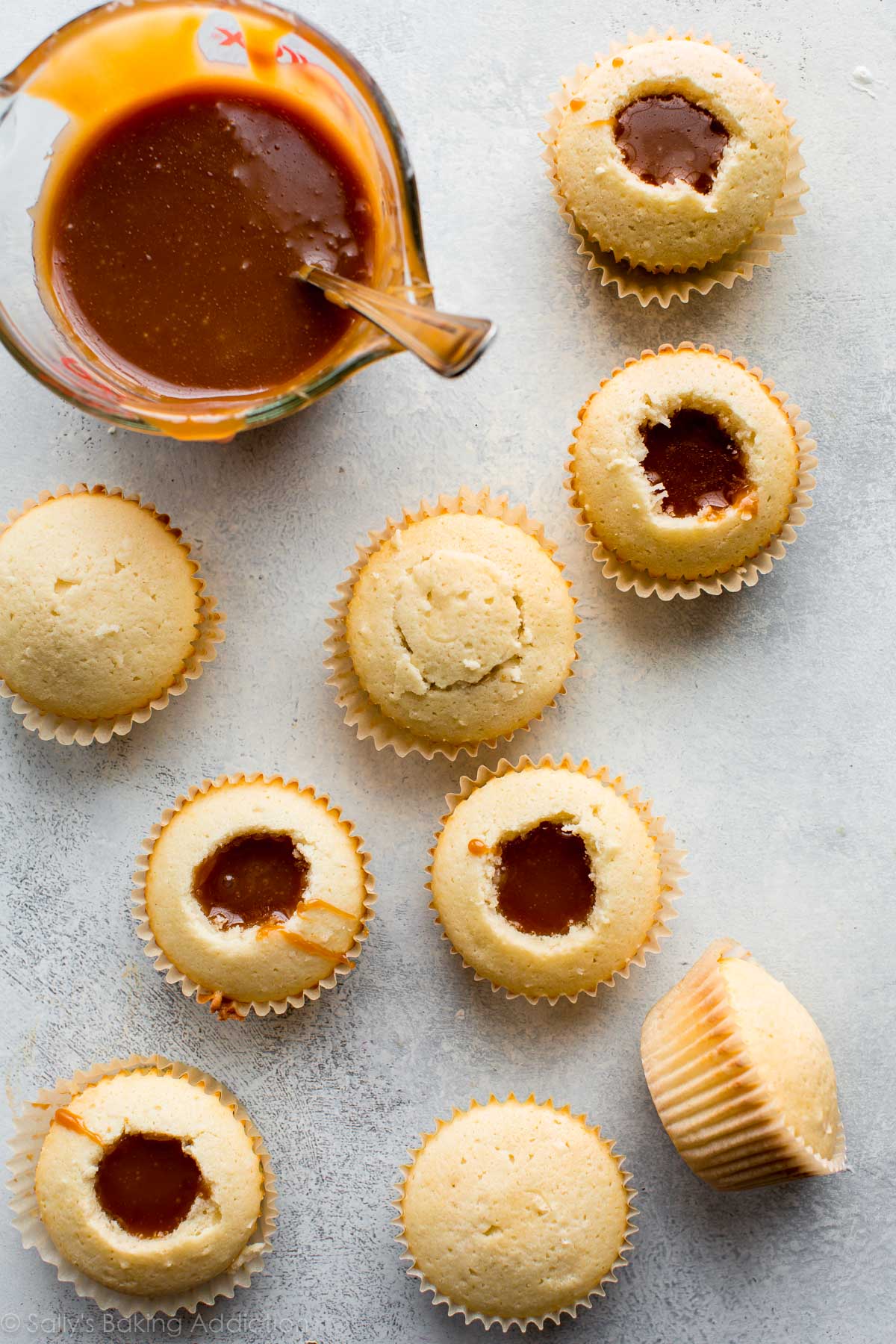 overhead image of coconut cupcakes with the center removed and filled with salted caramel sauce