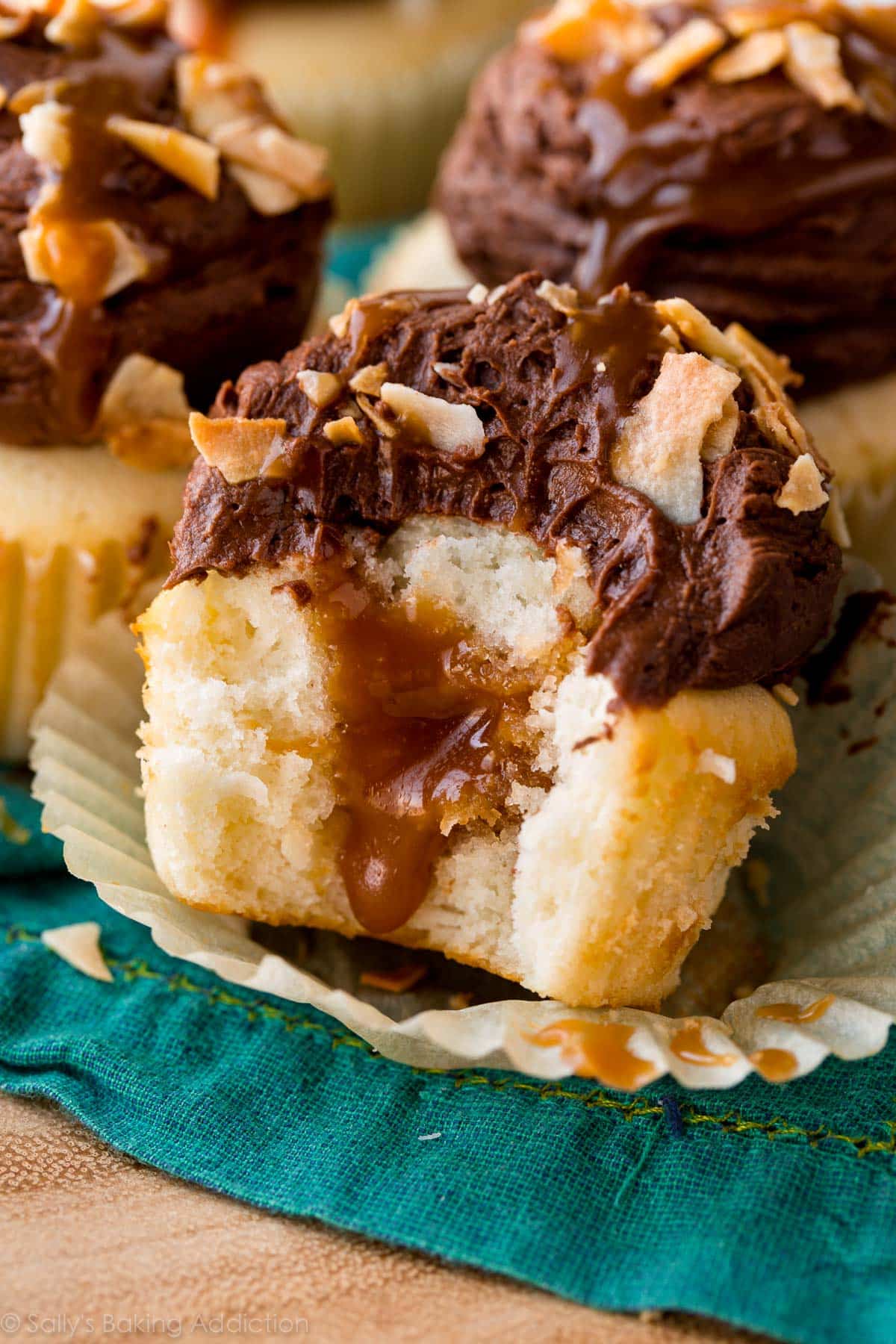 a bite out of a chocolate caramel coconut cupcake showing the caramel filling in the center