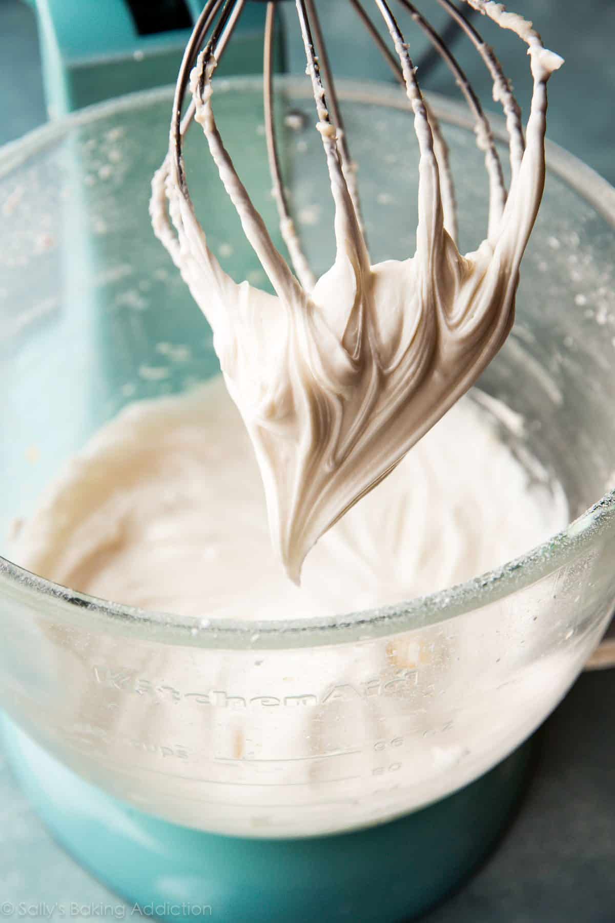 cream cheese frosting in a glass mixing bowl with whisk attachment