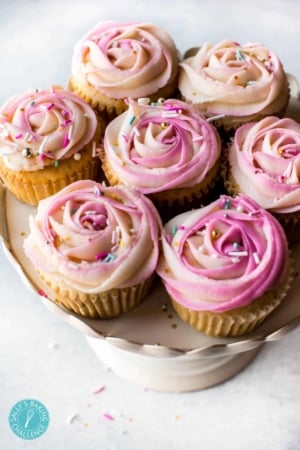 cupcakes with pink frosting roses on top on a cake stand