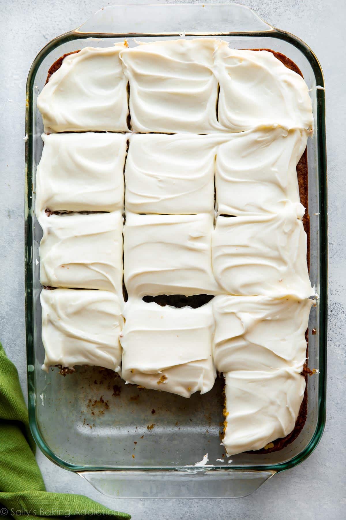 overhead image of pineapple carrot cake with cream cheese frosting in a glass baking dish cut into squares