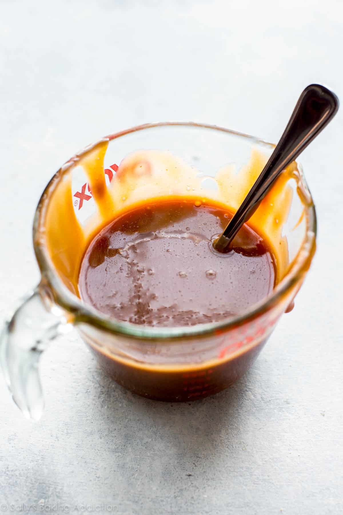 salted caramel in a glass measuring cup with a spoon