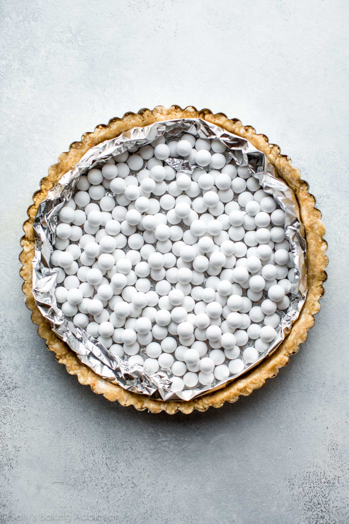 overhead image of pie weights on top of peanut crust in a tart pan