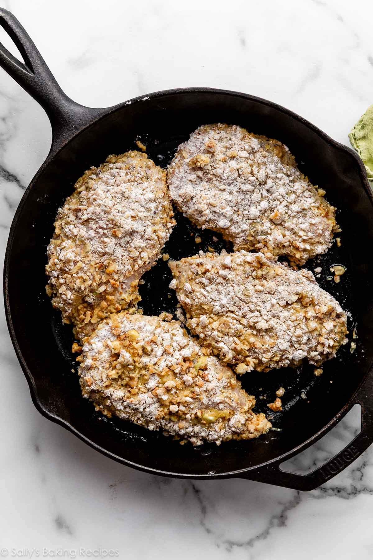coated chicken in cast iron skillet.