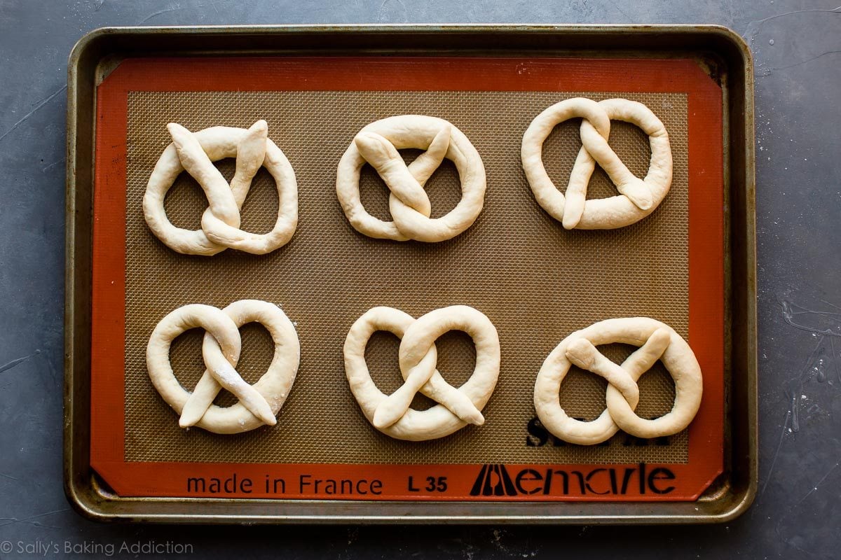 soft pretzel dough shaped into pretzels on a baking sheet before baking