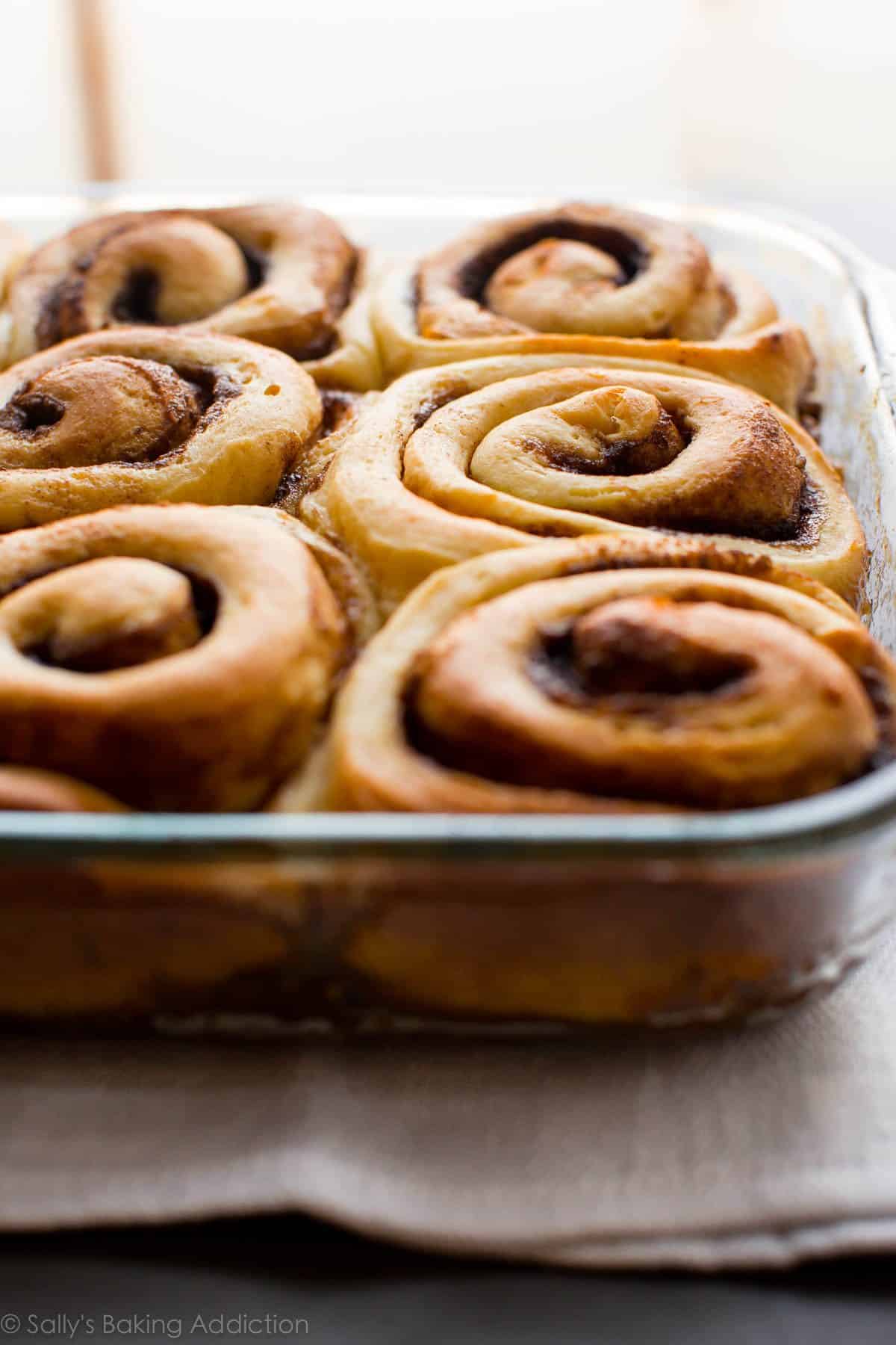 side view of maple pecan sticky buns in a glass baking dish after baking