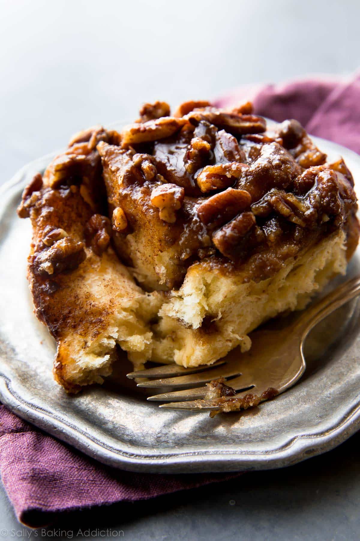 maple pecan sticky bun on a silver plate with a fork