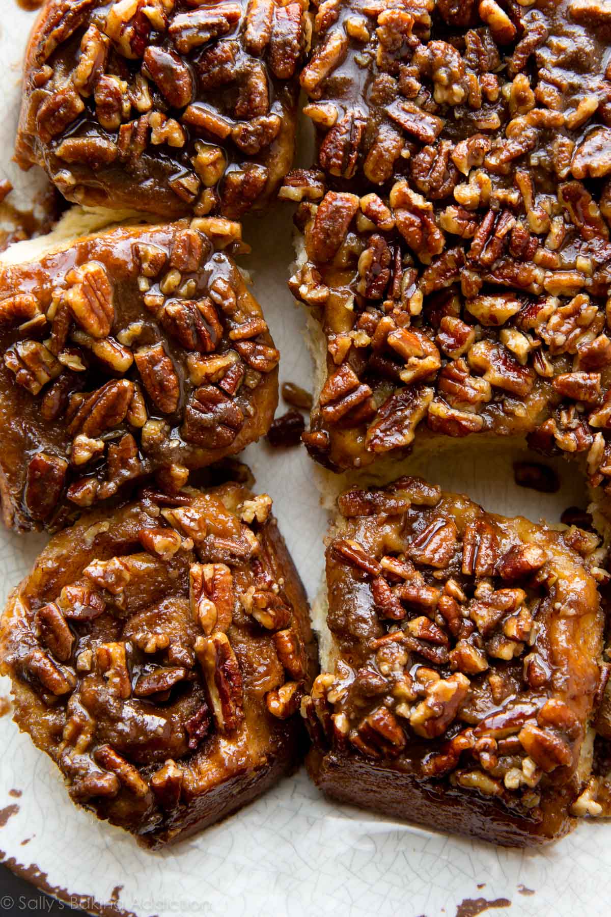 overhead image of maple pecan sticky buns with pecan topping on a white serving tray
