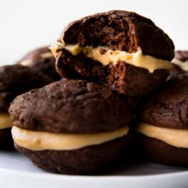 chocolate whoopie pies with salted caramel frosting on a white plate