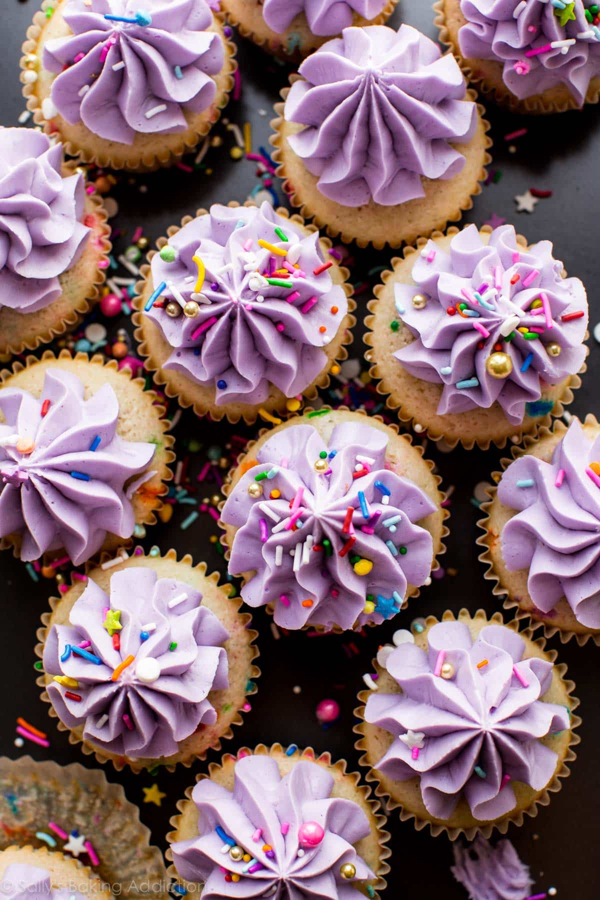 overhead image of funfetti cupcakes with purple frosting and sprinkles
